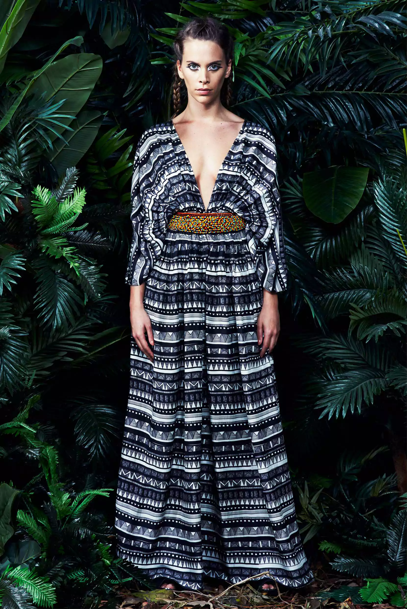 Deep neckline kaftan with tribal prints, gathered at the waist and detailed with hand bead embroidery, set against a studio backdrop.